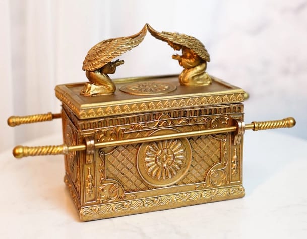 A gold box with two angels on top Description automatically generated