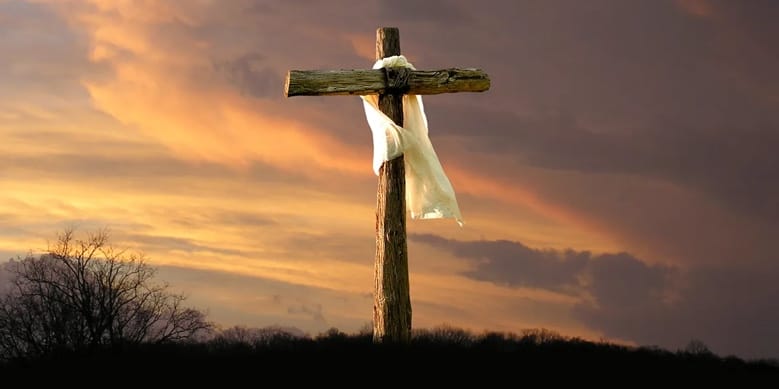 A wooden cross with a white cloth on it Description automatically generated